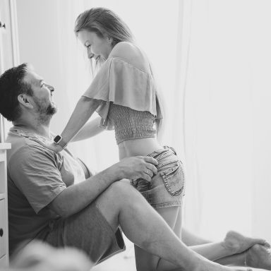 Homestories of love Eine Frau steht lächelnd vor einem Mann, der auf dem Boden sitzt. Helle, freundliche Atmosphäre.